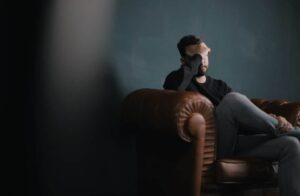 man sitting on couch with head in hands