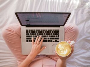 woman with laptop on her lap holding a cup of coffee